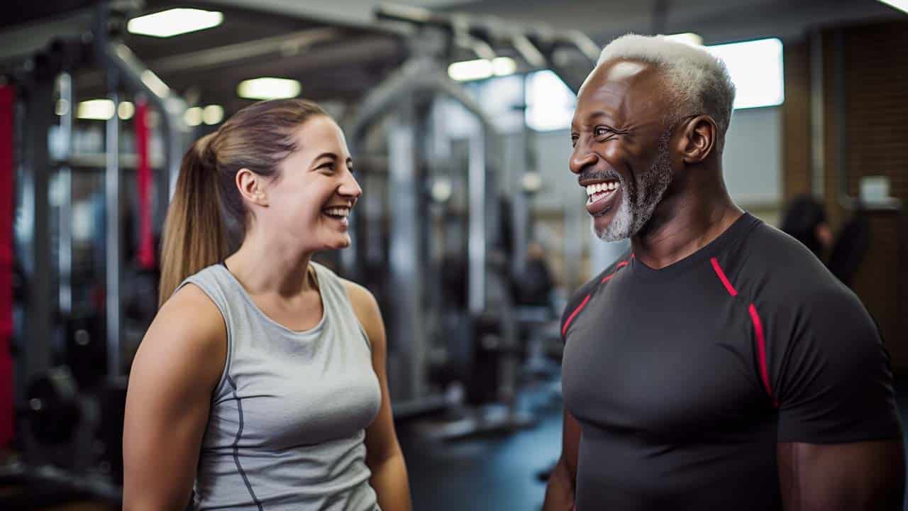 man aged 60+ years talking to female fitness trainer at the gym.