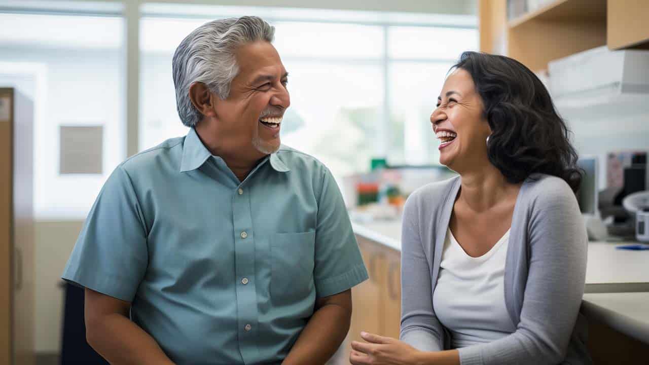 Hispanic man in his 60's talking with a nurse in a medical clinic.